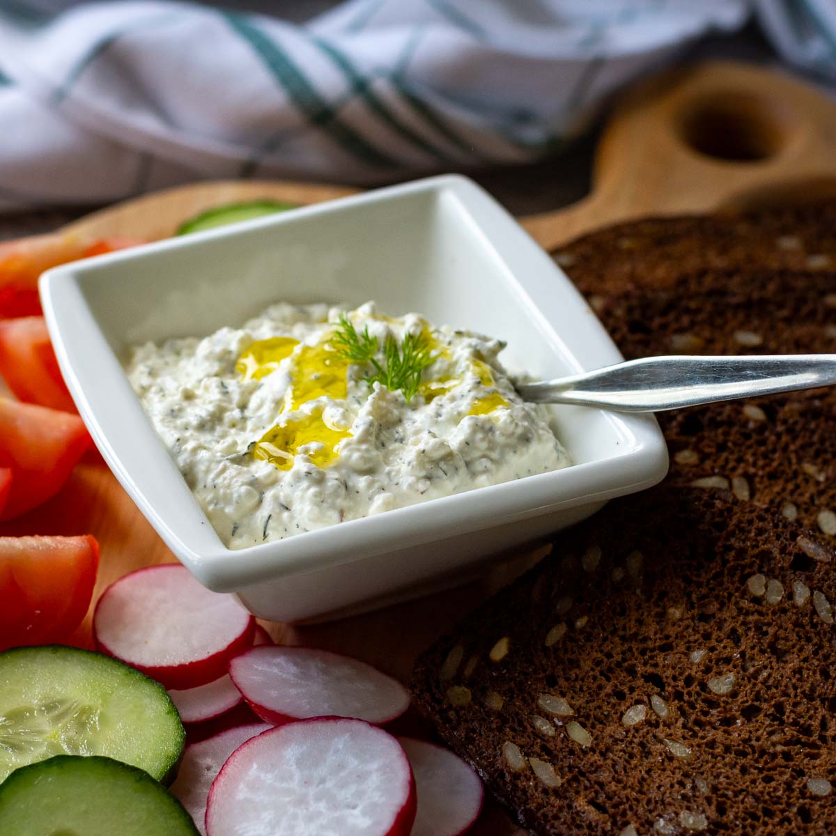 Lithuanian Farmer's Cheese Dip and Spread in a small square white bowl with a spoon it.