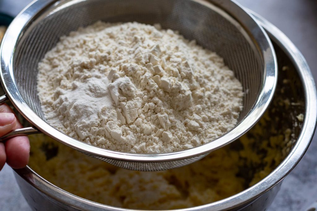 Flour and baking soda in a large fine sieve over the bowl with butter mixture.