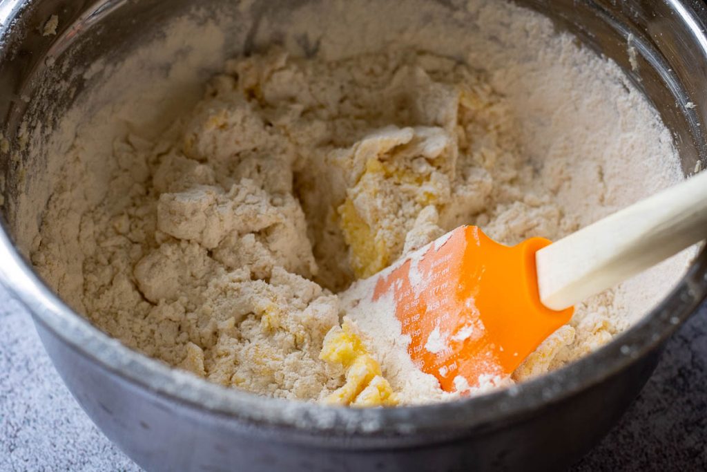 Mixing the Lithuanian cookie dough with an orange spatula.