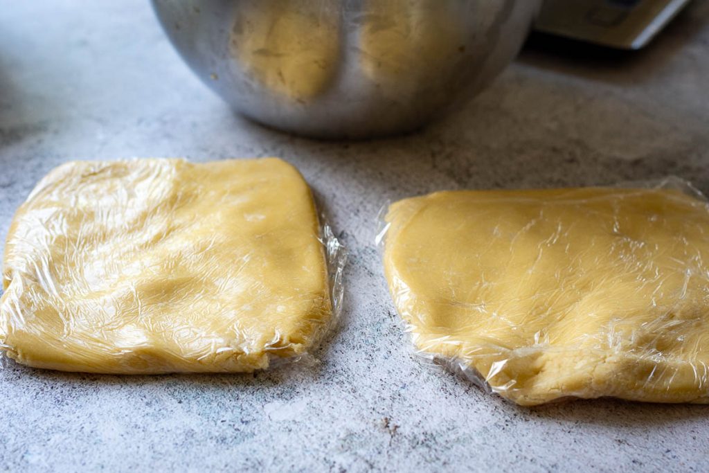 Two pieces of cookie dough wraped in plastic wrap.