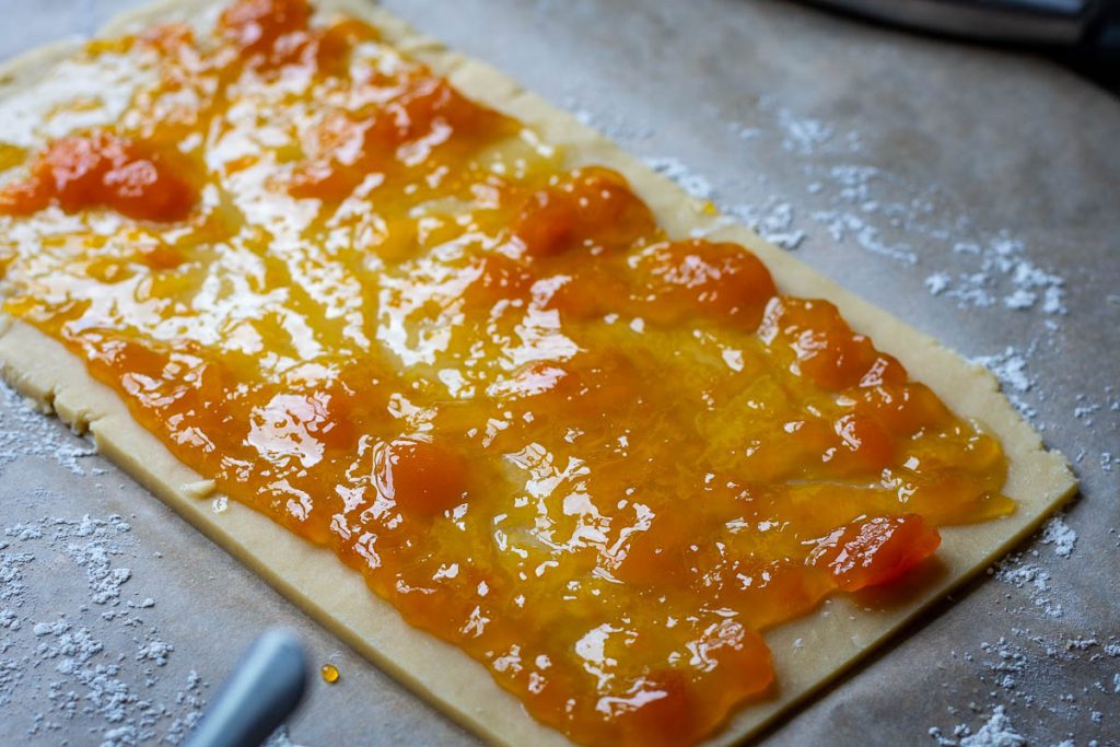 Rolled out Lithuanian cookie dough with jam spread on top.