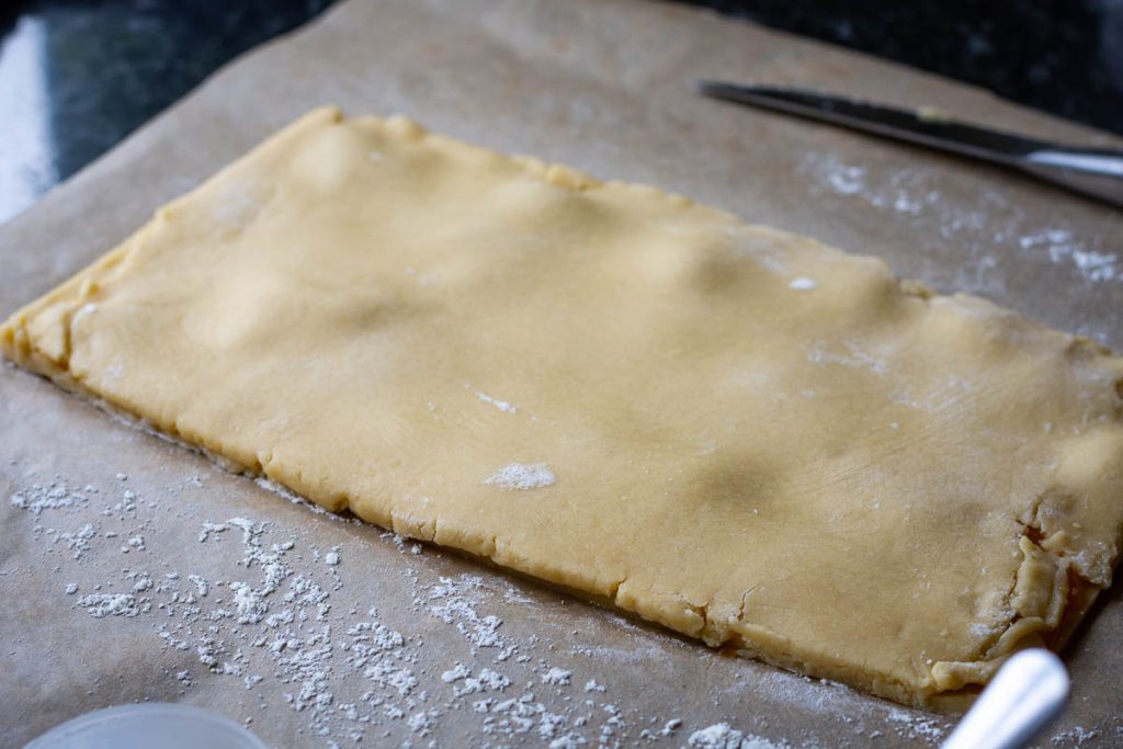 Jam sandwiched between two sugar cookie dough sheets.