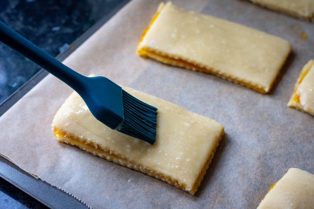 Brushing the cookies with egg wash.