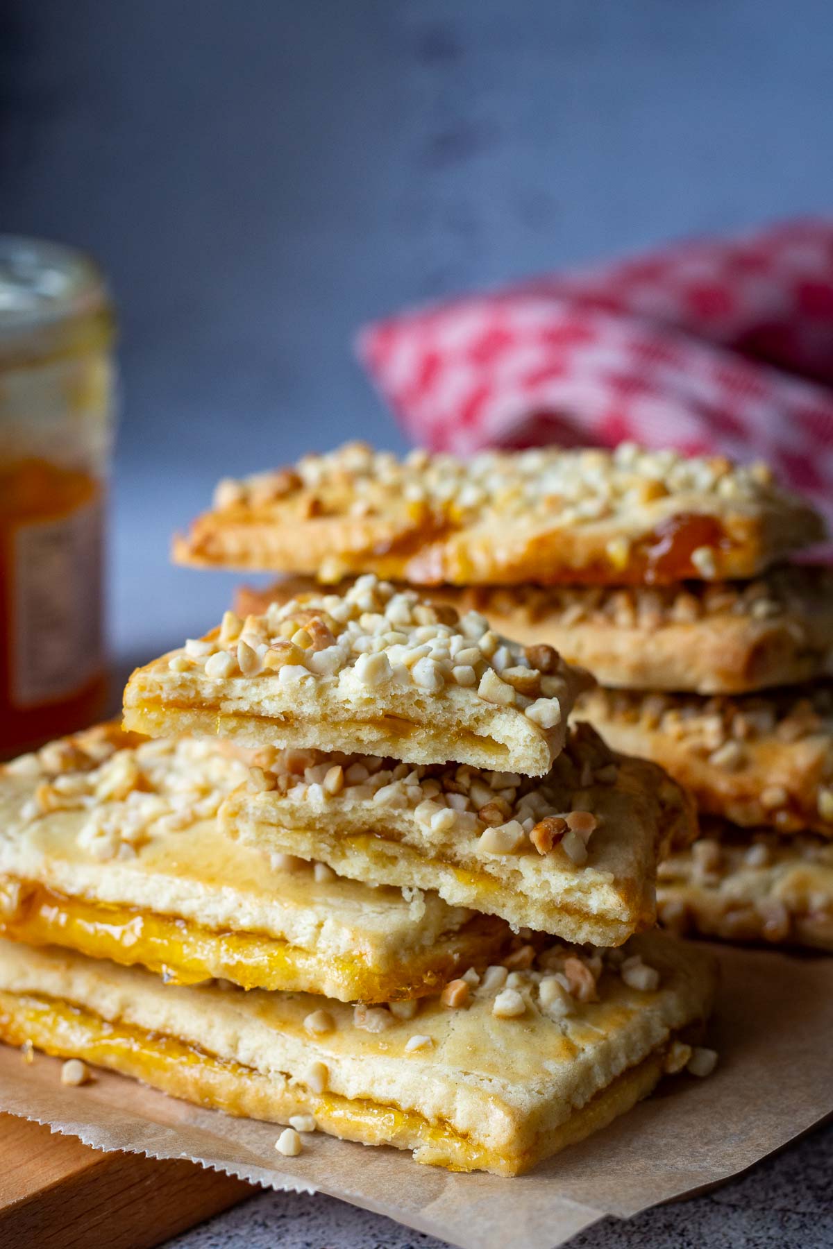 A stack of Lithuanian Jam-Filled Sugar Cookies with nut topping on a wooden board.