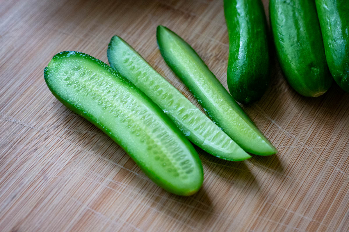 Baby English cucumbers on a wooden chopping board.