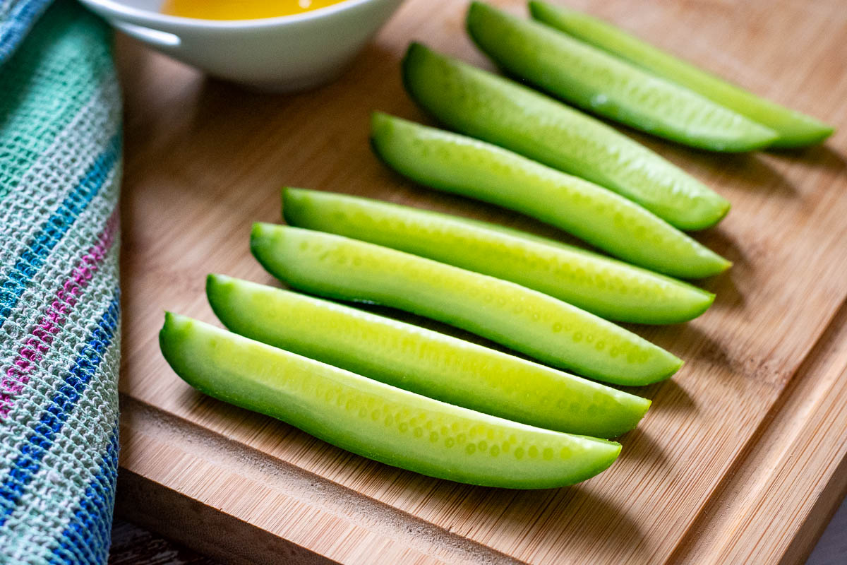 Cucumber sticks arranged on a large wooden board.