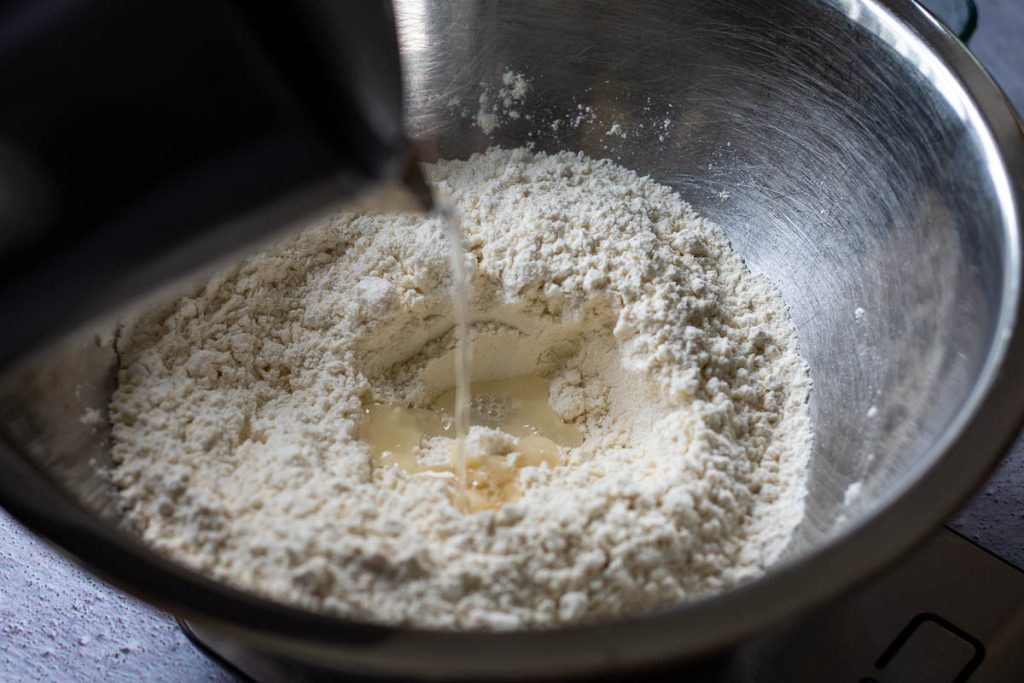 Pouring boiling water from the kettle into the flour and salt mixture.