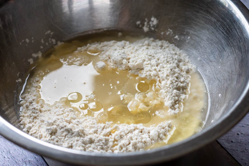 Water and oil poured iover the dry ingredients for Lithuanian dumplings.