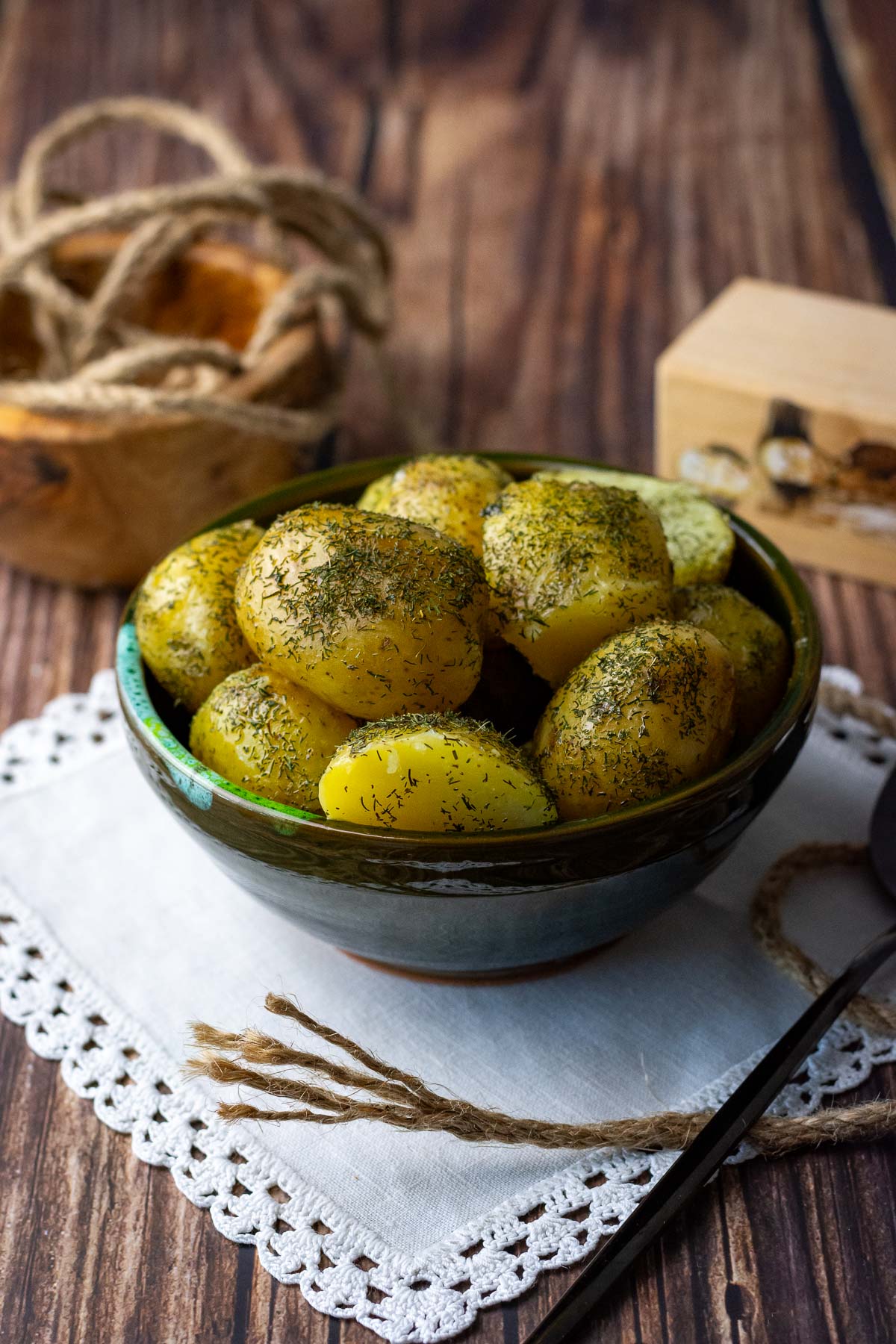 Boiled potatoes with dill and butter in a small green bowl served as a side dish.