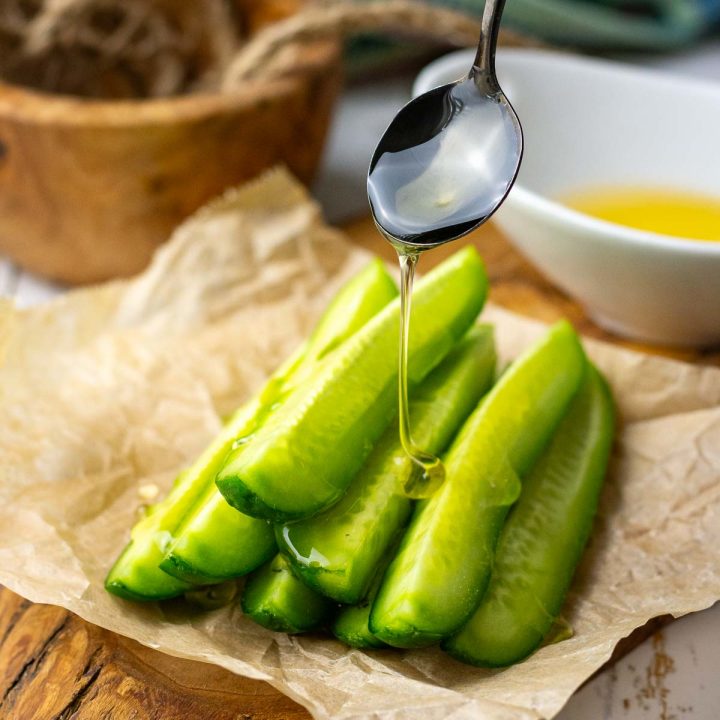 Cucumber sticks being drizzled with honey.
