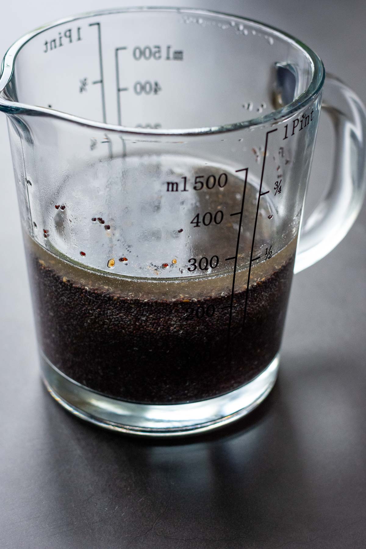 Poppy seeds soaking in hot water in a glass jug. 