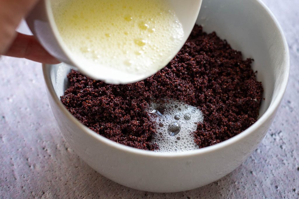 Adding lightly whisked egg white to the poppy seeds. 