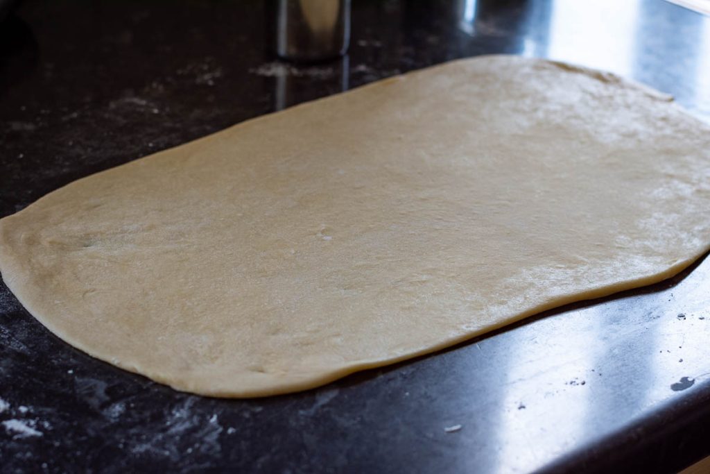 The bun dough rolled into a large rectangle. 