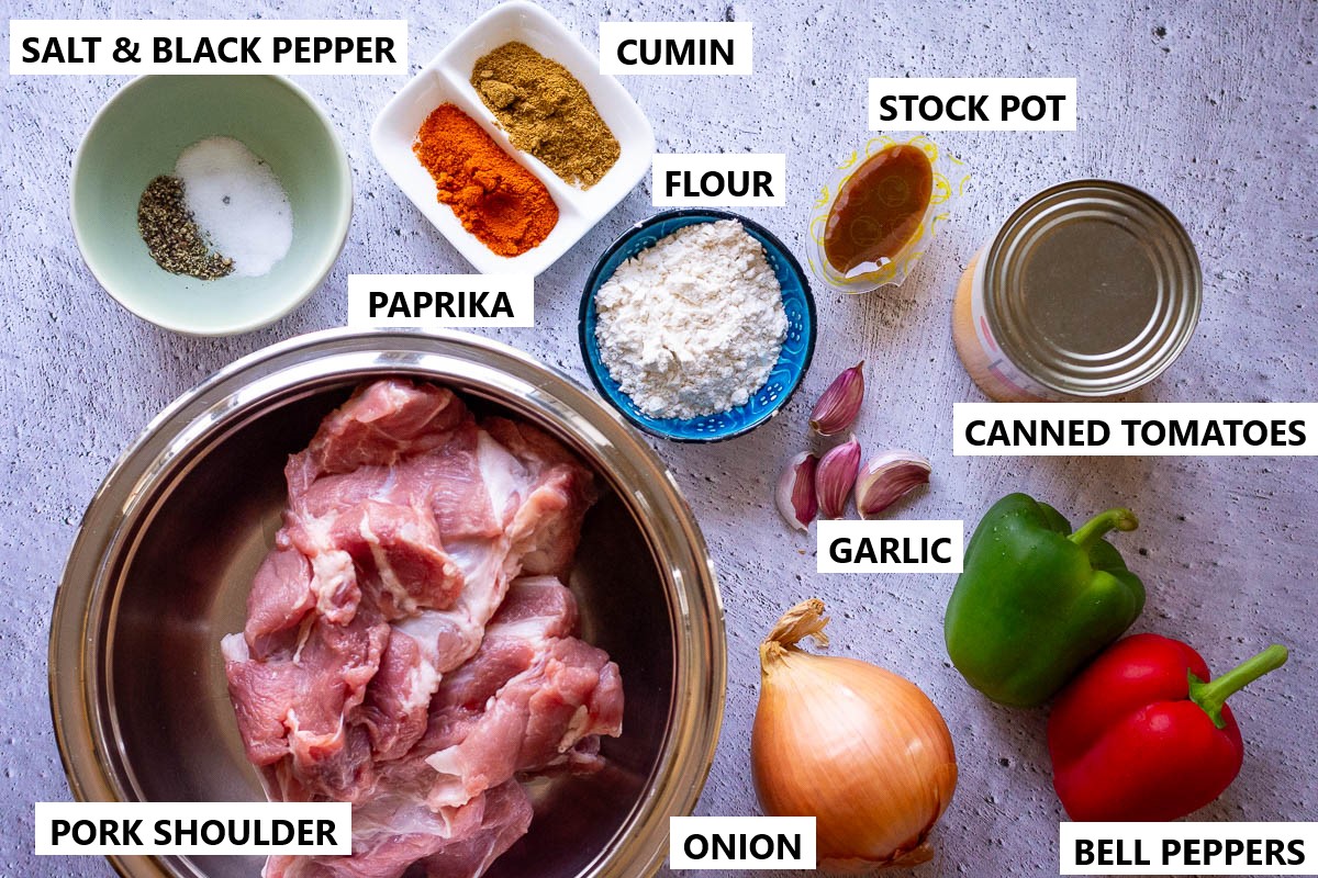 Ingredients for pork goulash on a light grey table.