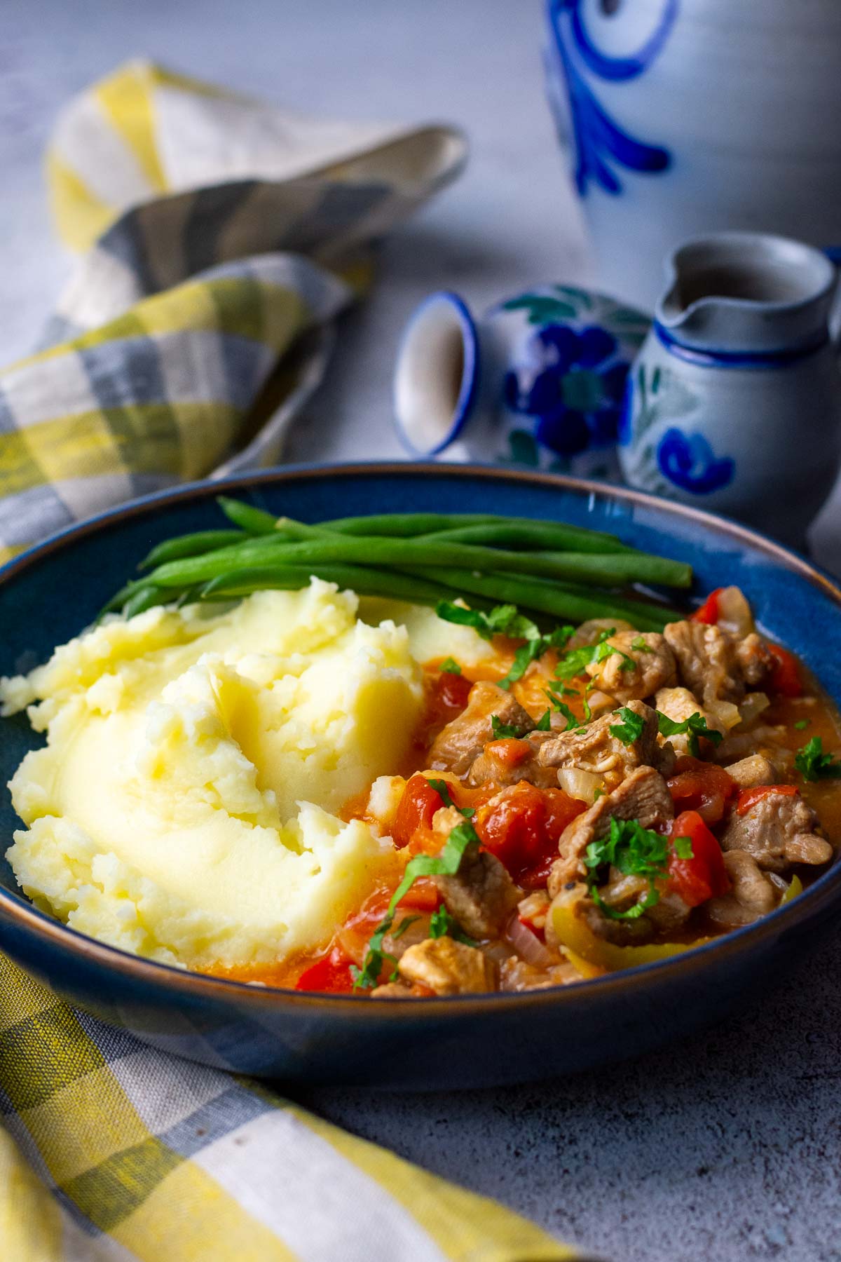Lithuanian Pork Goulash served with mashed potatoes and green beans in a blue bowl.