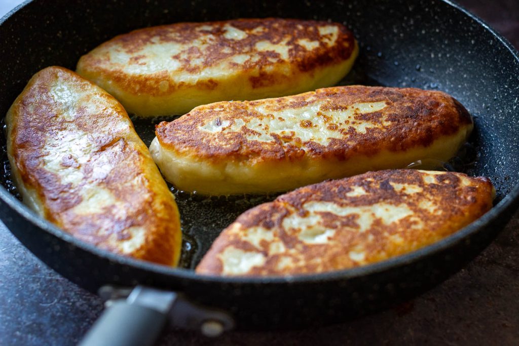 Golden brown lithuanian potato pancakes frying on their second sides.