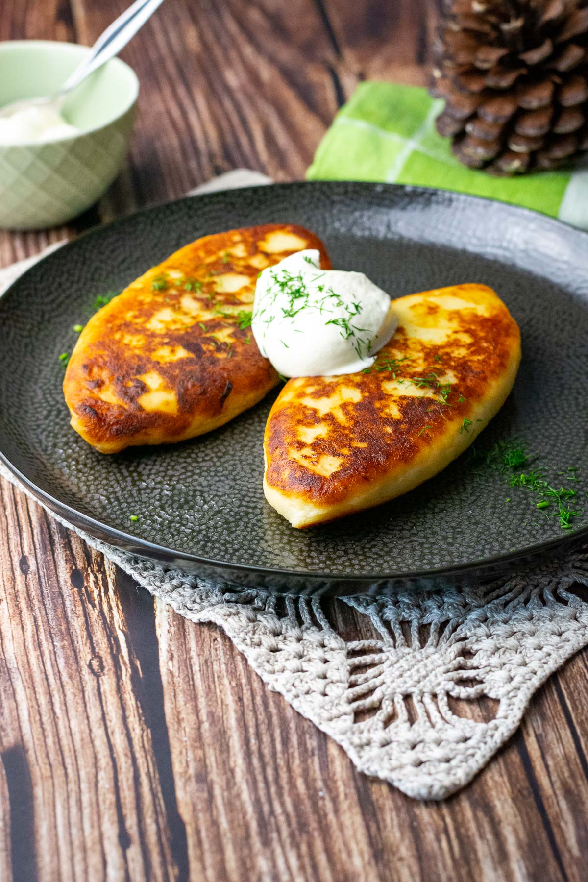 Lithuanian potato pancakes stuffed with meat on a black plate with sour cream.