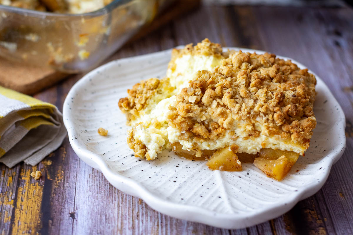 A portion of apple cheesecake crumble on a white plate.