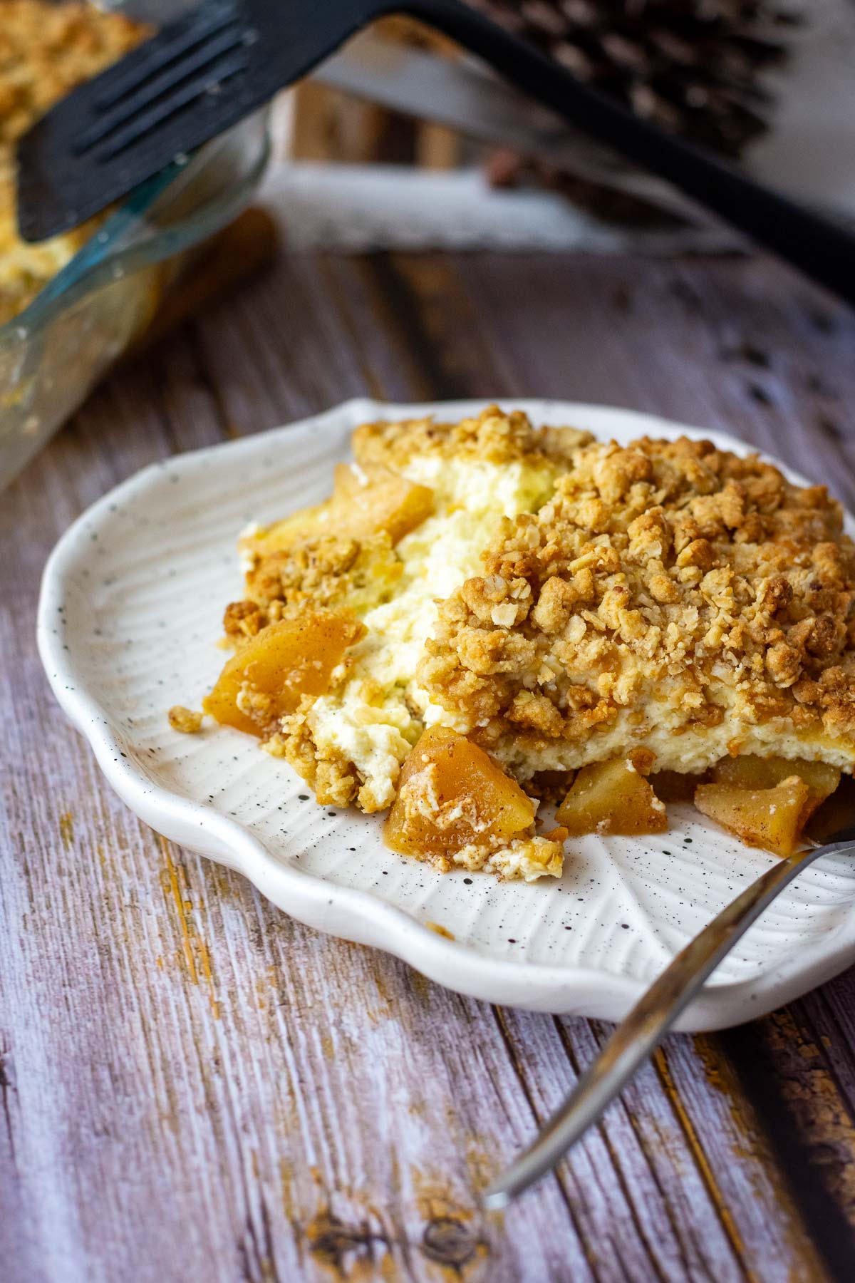 A portion of apple cheesecake crumble on a white plate.