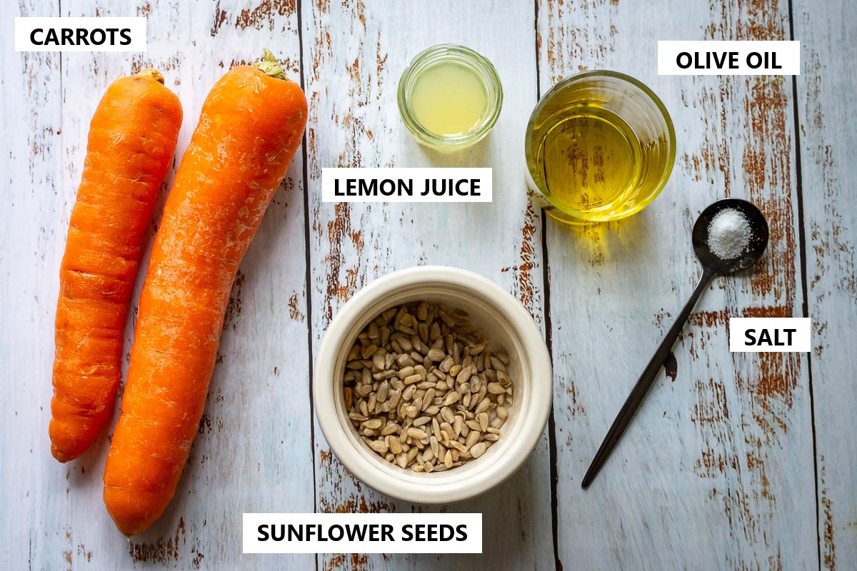 Ingredients for LIthuanian carrot salad on a rustic white wooden table.