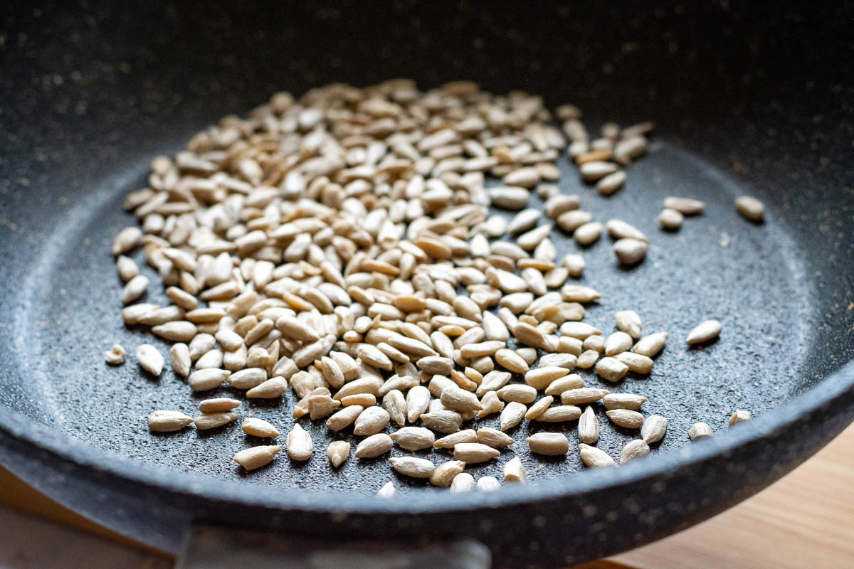 Toasting sunflower kernels in a small frying pan.