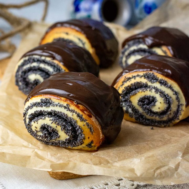 Lithuanian Poppy Seed Buns Coated in Chocolate Ganache on a piece of baking parchment.