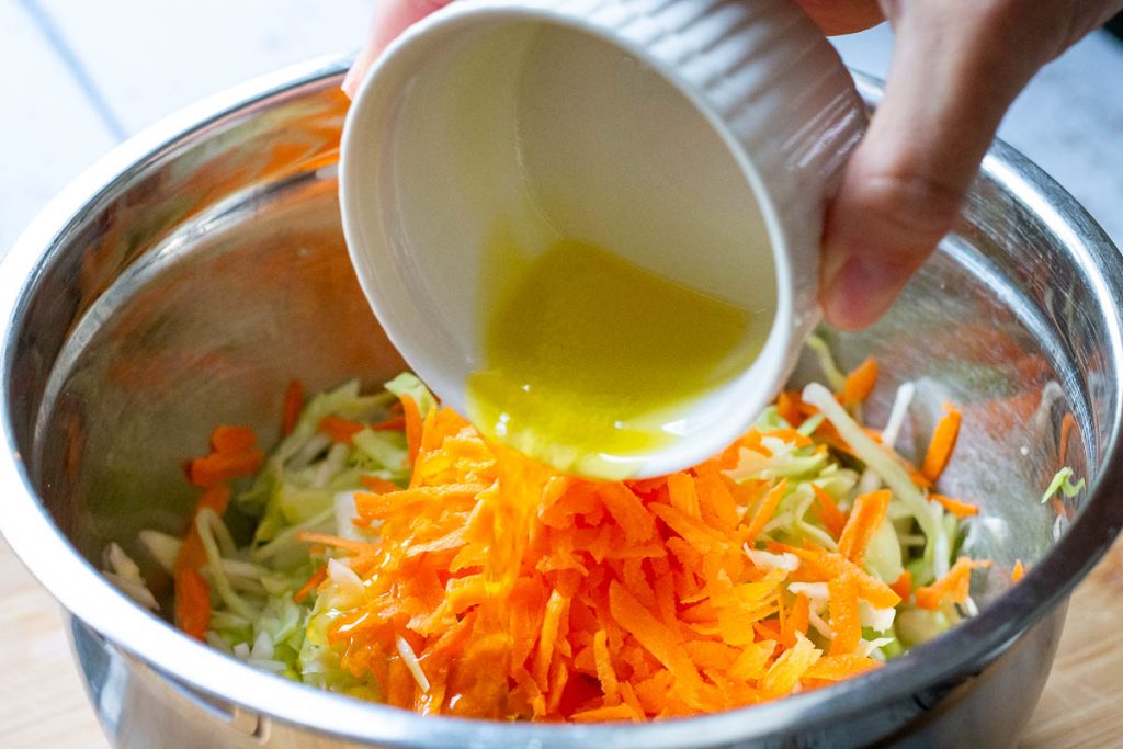Pouring the simple dressing over the cabbage and carrot salad.