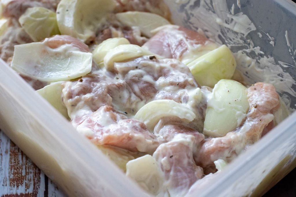 Chicken, onions, mayo, lemon juice, oil and seasoning mixed in a Typperware box for marinating.
