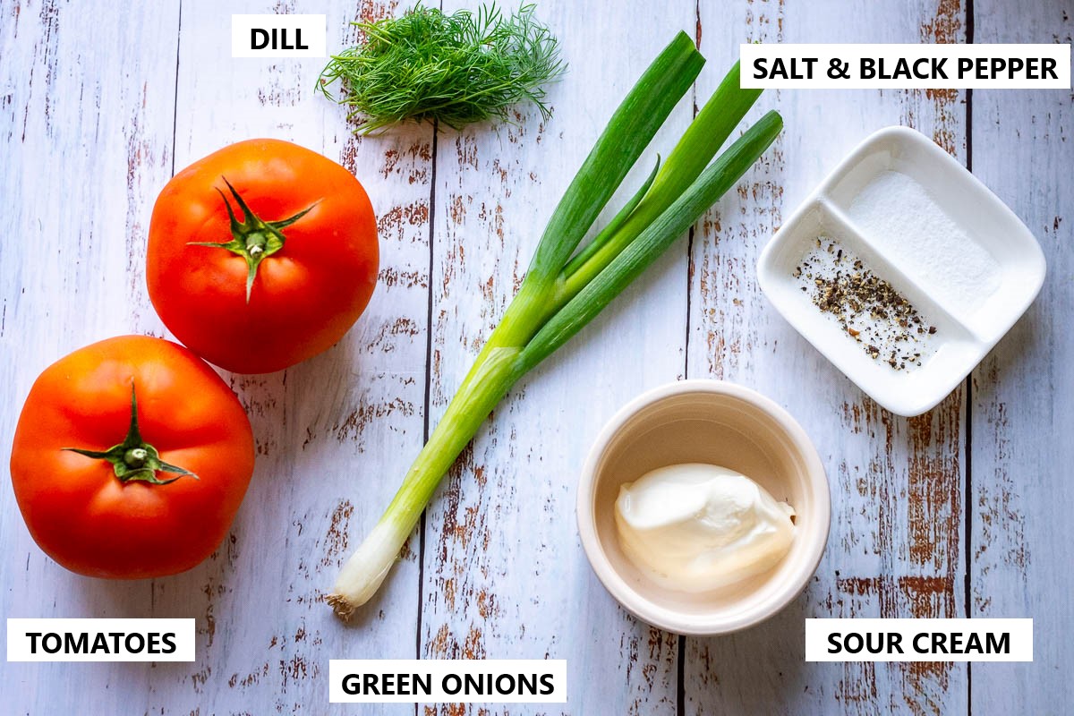 Ingredients for Tomato salad on a rustic wooden white table.