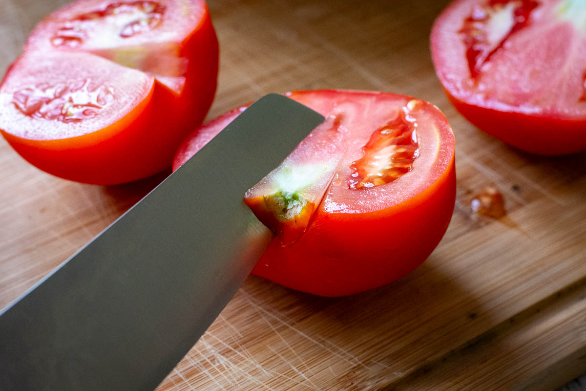 Cutting out tomato stalks using a sharp knife.