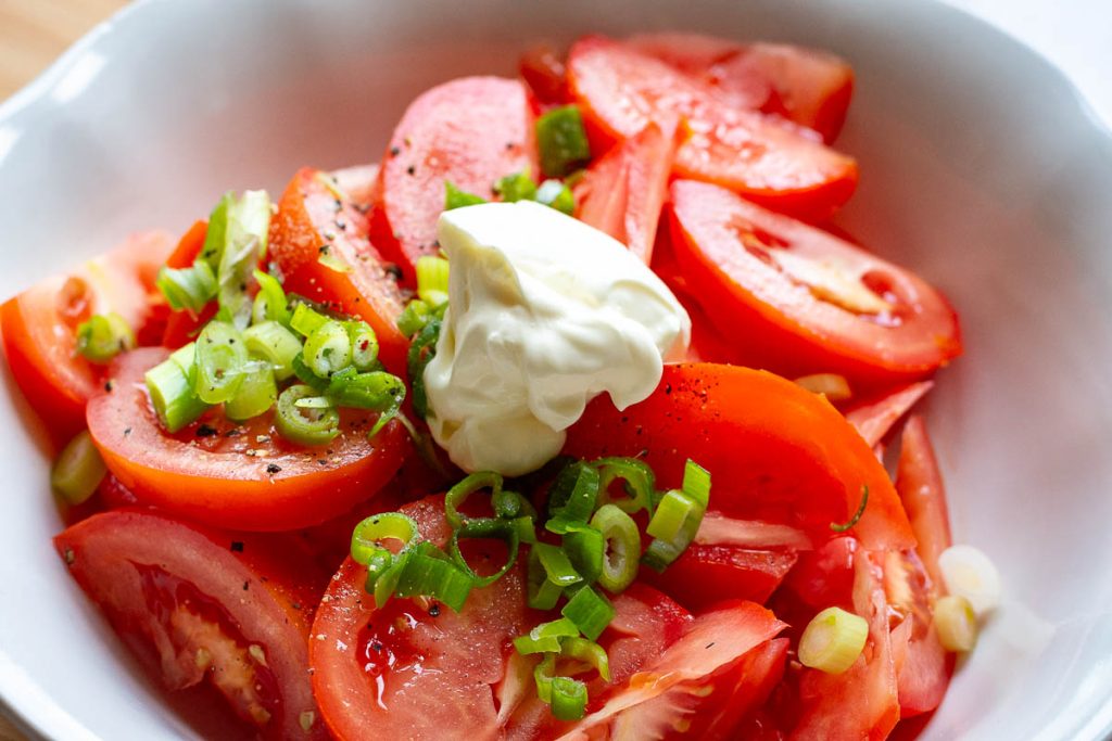 Tomato wedgs with green onion and sour cream on top.