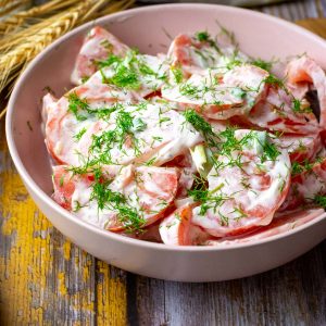 Lithuanian Tomato Salad With Onions and Dill in a pink bowl.