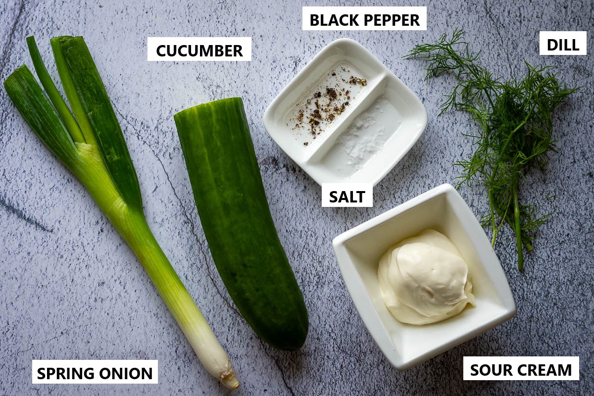 Ingredients for Cucumber and Sour Cream Salad on a grey surface. 