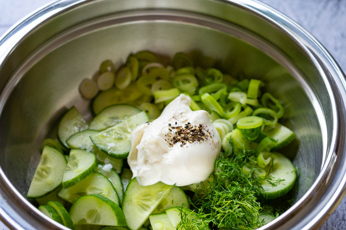 All ingredients for cucumber salad in a metal bowl. 