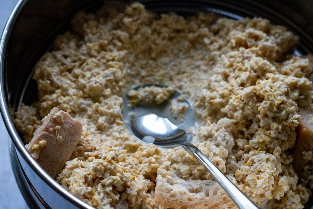 Squeezing the oats through a fine sieve with the back of a spoon.