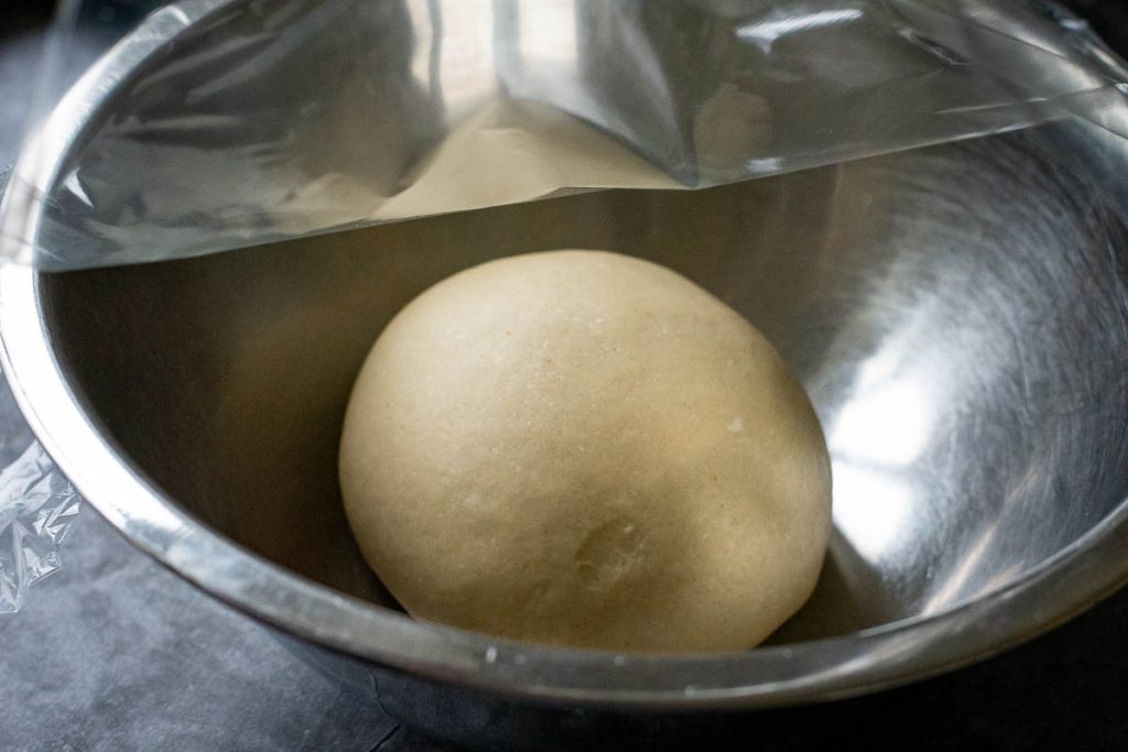Sweet dough for the buns in a metal bowl before proofing.