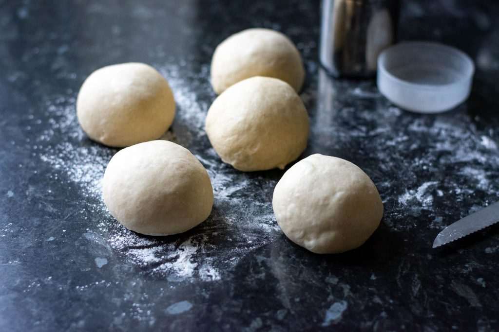Five balls of dough on a lightly floured surface.