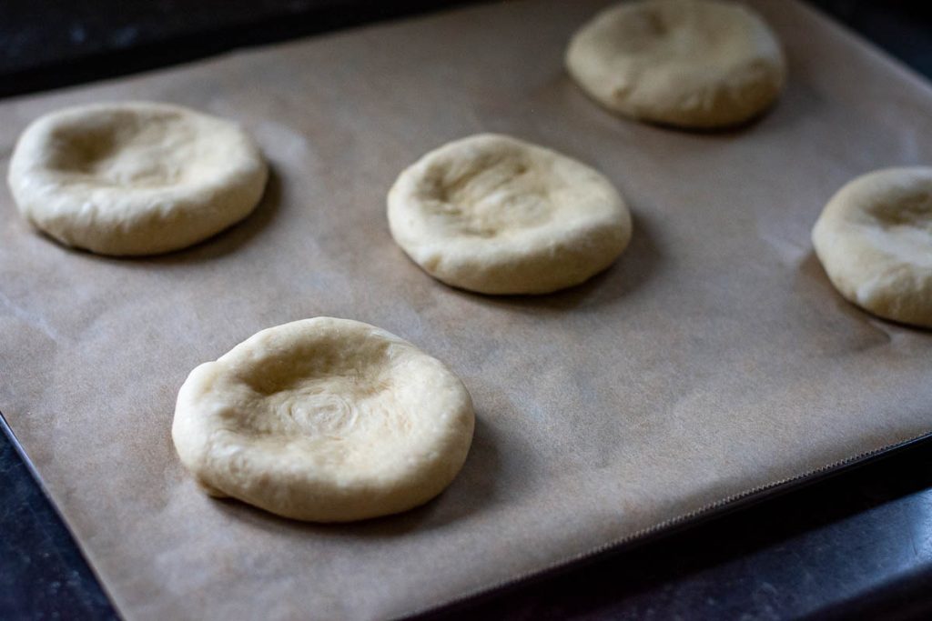 Sweet bun dough shapes into rounds with dips in the middle of each.