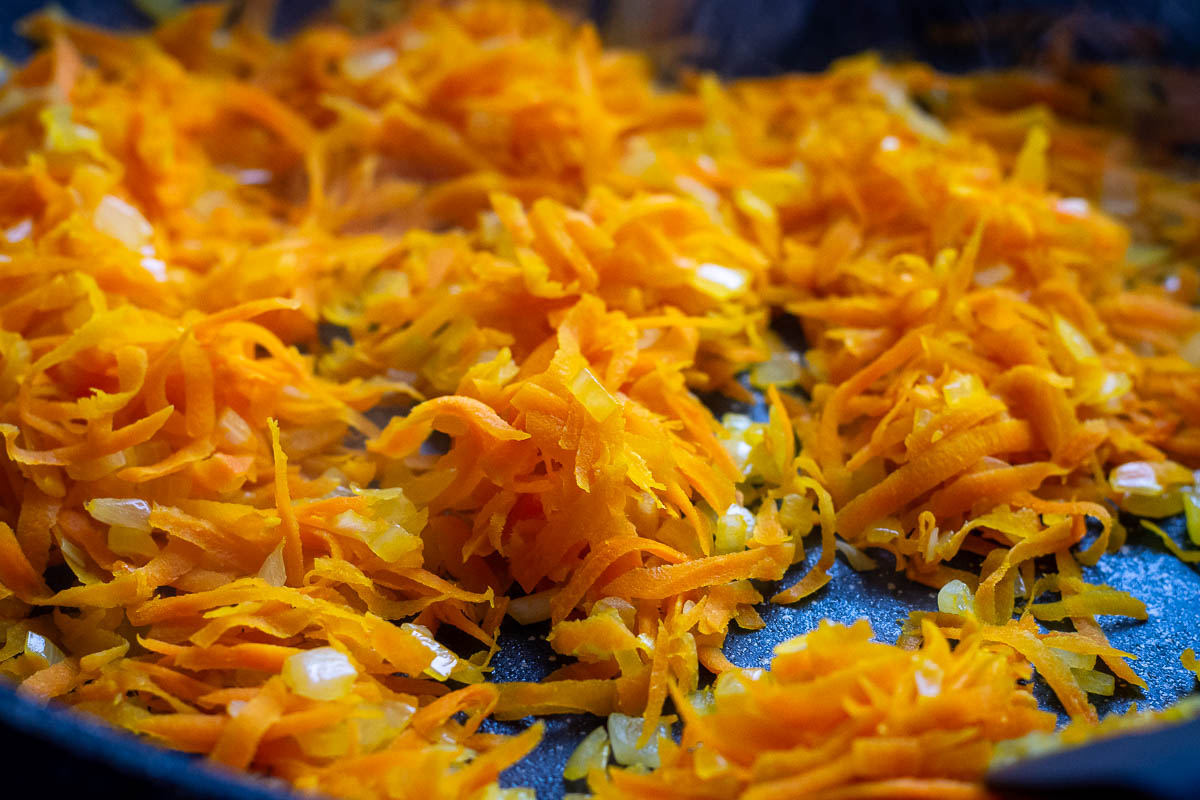 Sauteed carrots and onions in a frying pan.