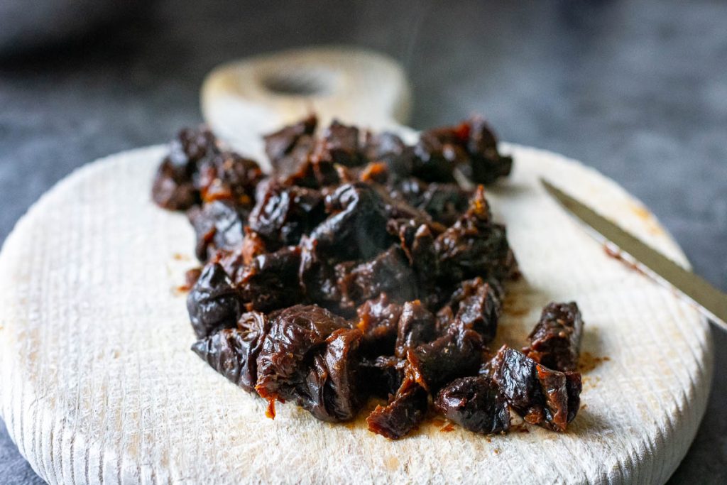 Dates roughly chopped on a wooden board.