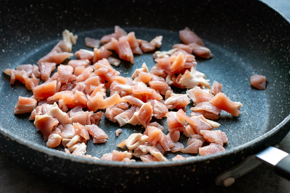 Small pieces of bacon in a frying pan.