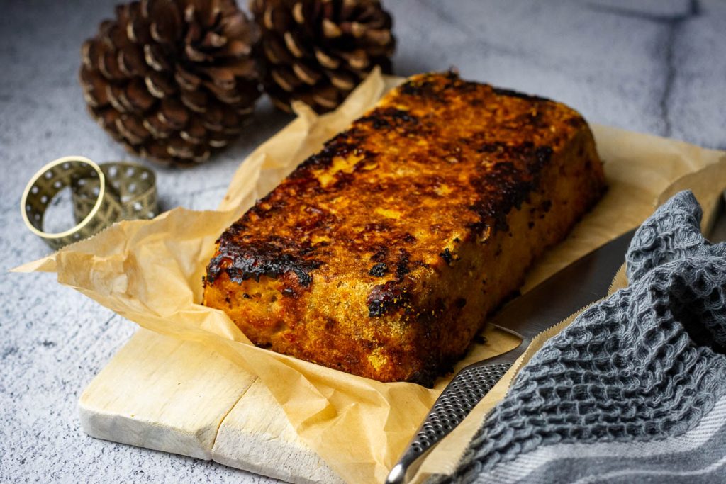 Lithuanian meatloaf with apples and bacon inverted onto a iece of parchment paper.