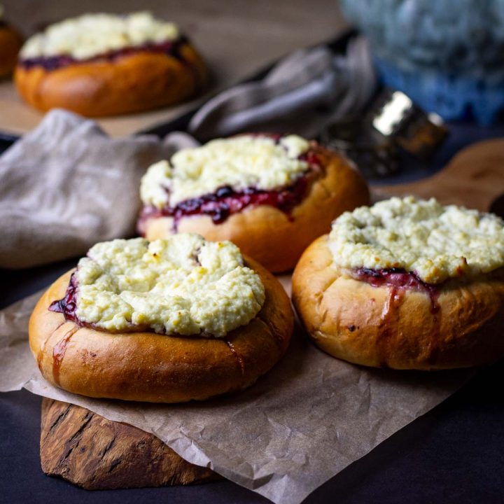 Three Lithuanian Sweet Cheese Buns on a wooden board.