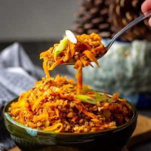 Lithuanian Buckwheat with carrots and onion being picked up by a spoon.