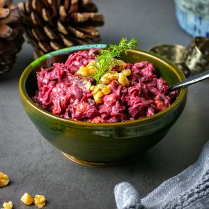 Beetroot, prune and walnut salad in a small bowl garnished with a sprig of dill.