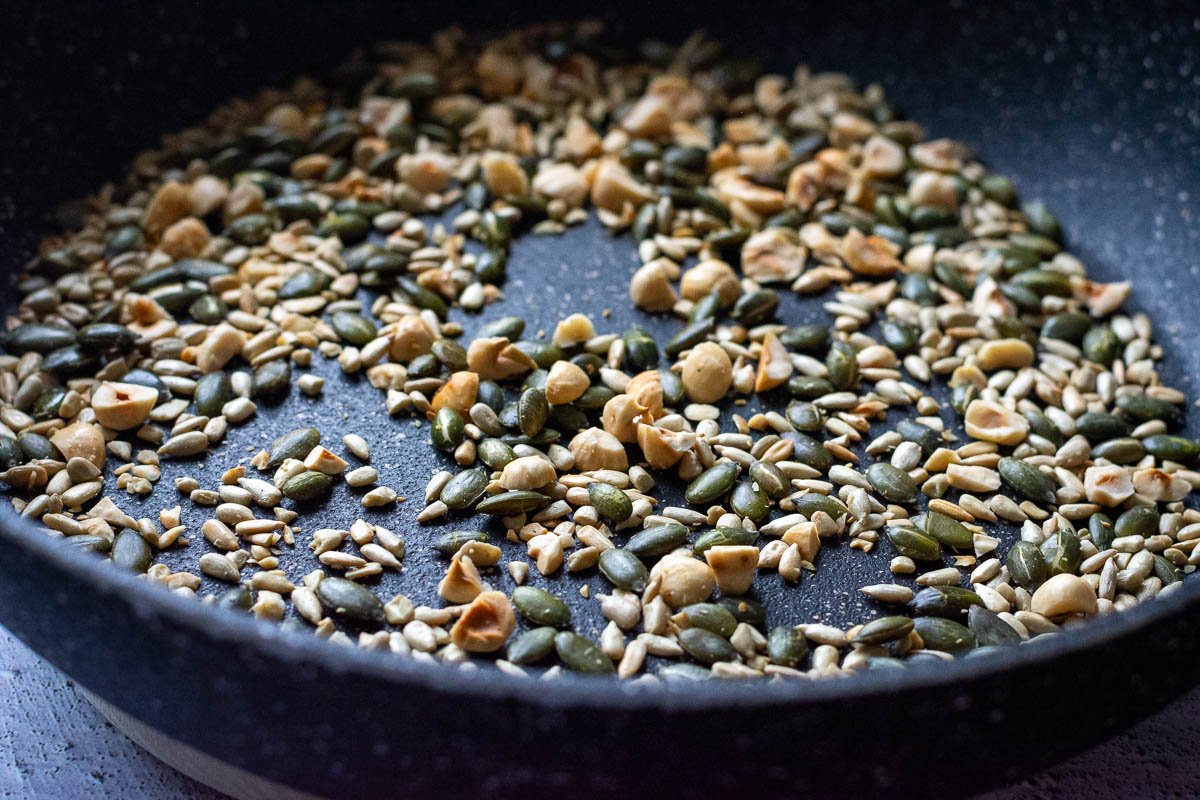 Hazelnuts, sunflower and pumpkin seeds toasting in a dry frying pan.