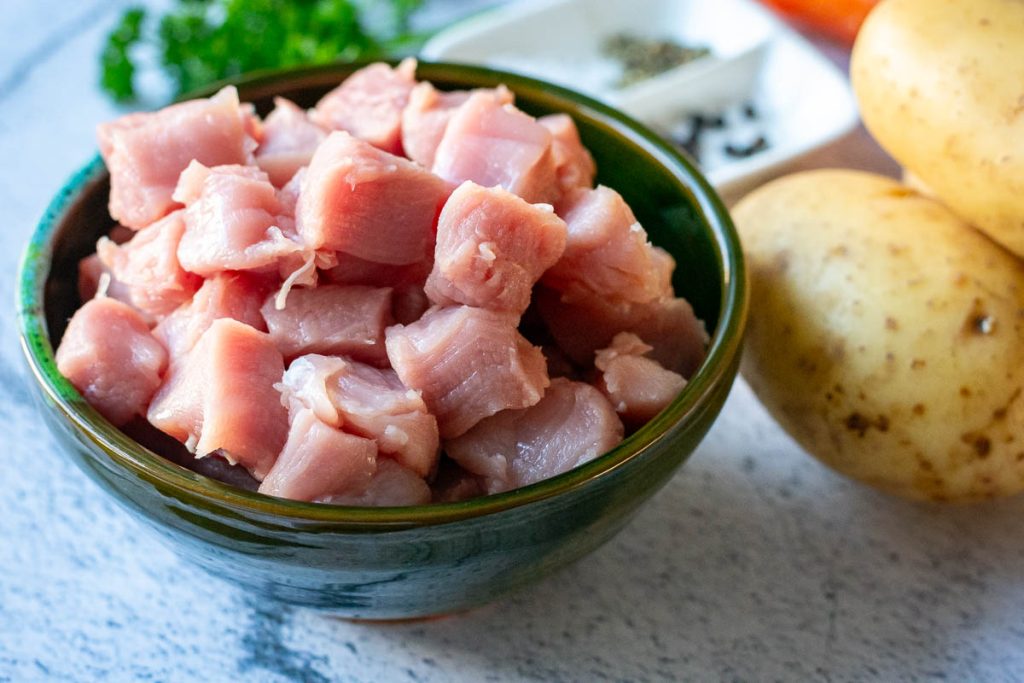 Cubed pork in a small green bowl.