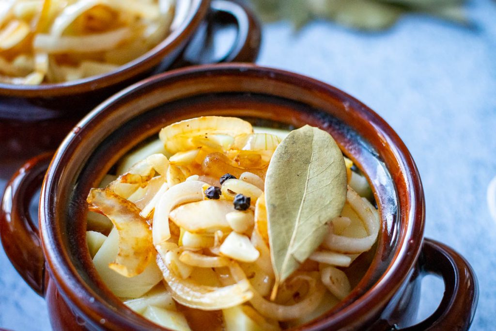 Clay pot stew topped with peppercorns and a bay leaf.
