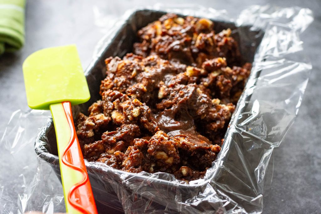 Lazy cake mixture spooned into a loaf tin lined with plastic wrap.