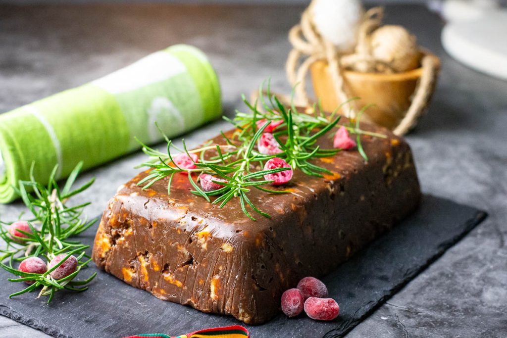 Uncut Lithuanian Lazy Chocolate cake decorated with rosemary sprigs and cranberries.